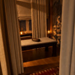 Łóżko do masażu za jasnymi zasłonami w ISLA Massage & Spa